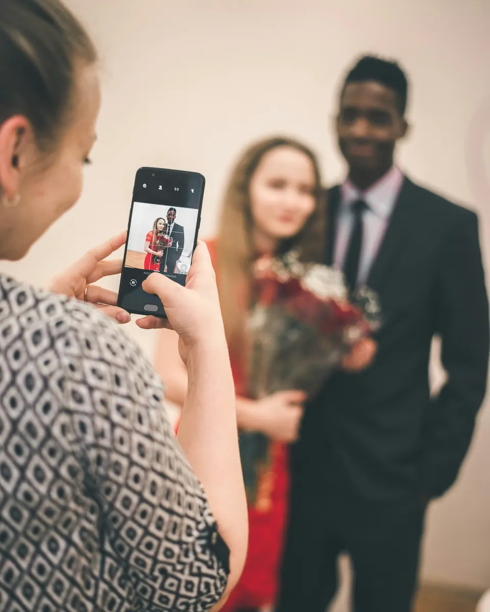 A guest photographing a smiling couple on her phone