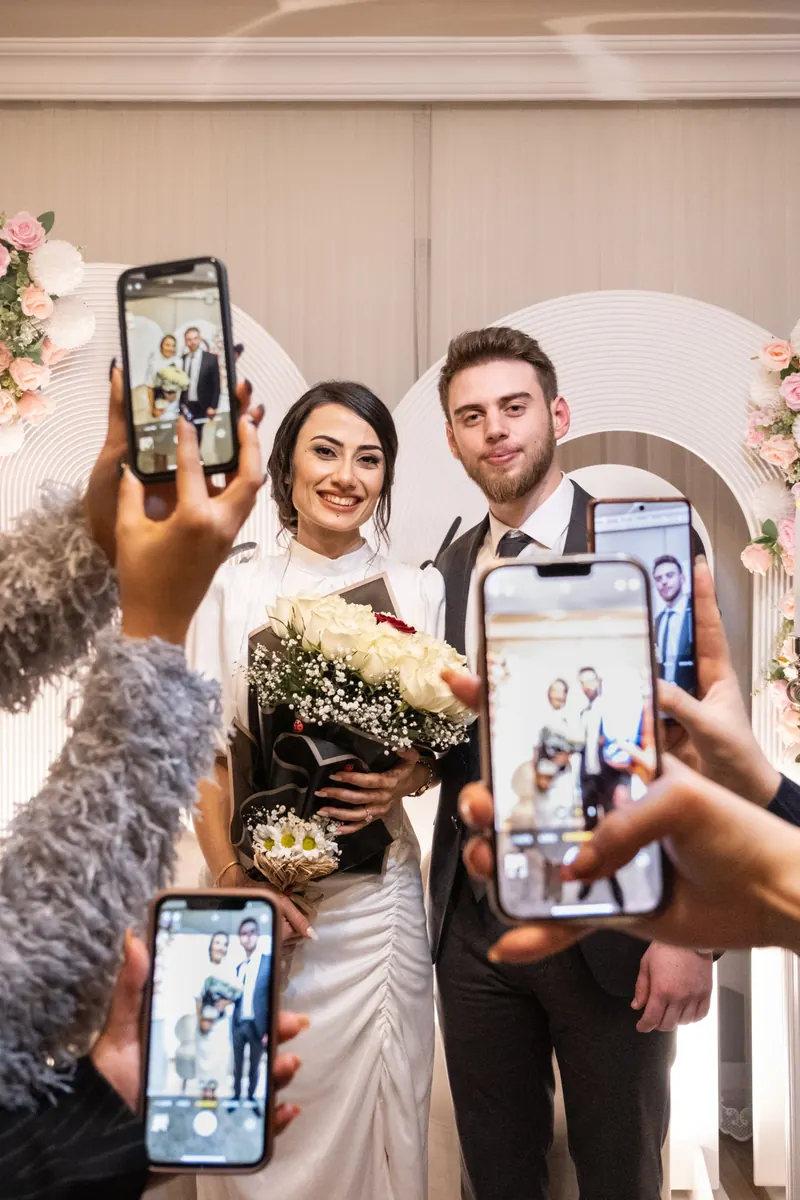Guests holding up their phones to photograph a newly married couple